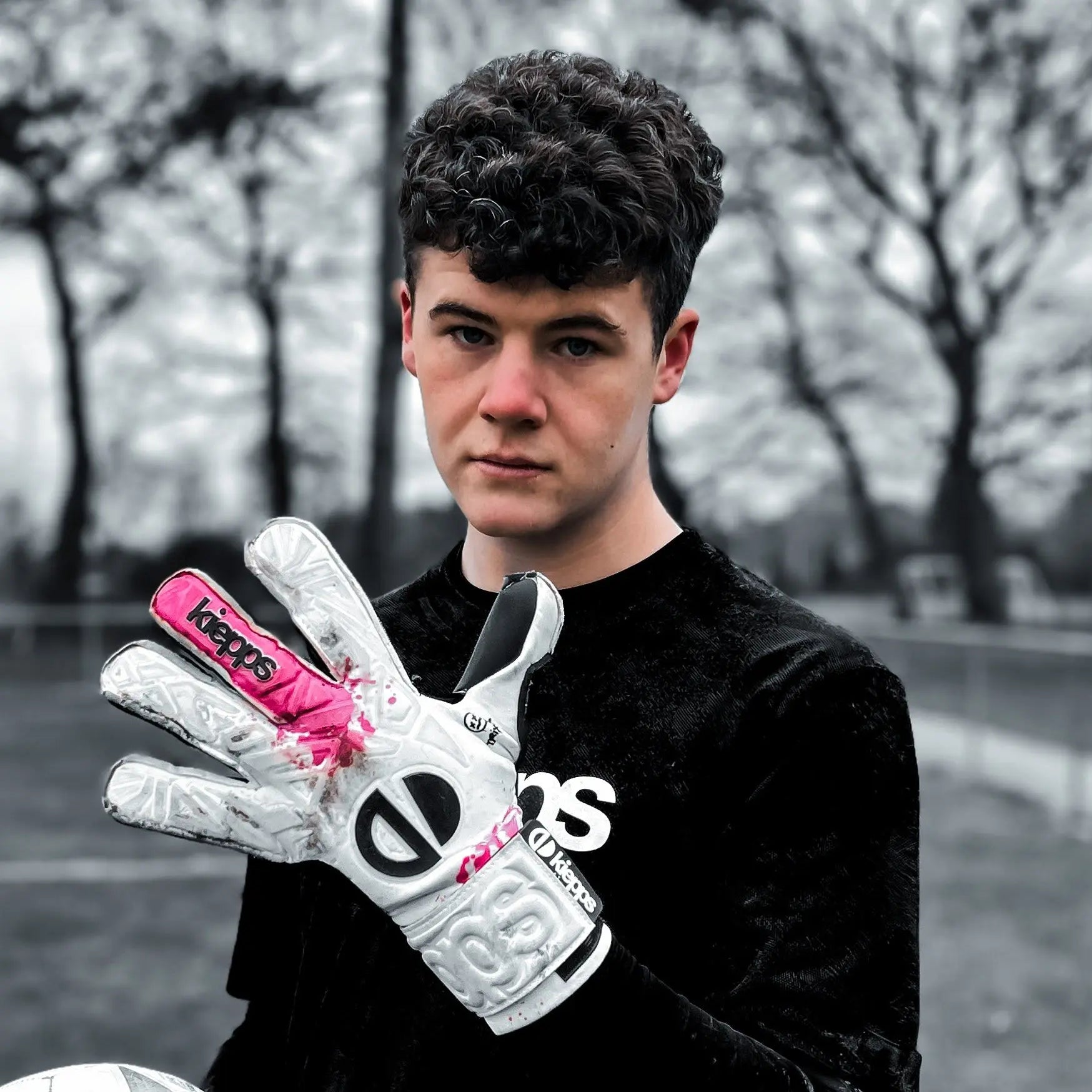 Person wearing a black shirt and white gloves with pink accents, standing outdoors.