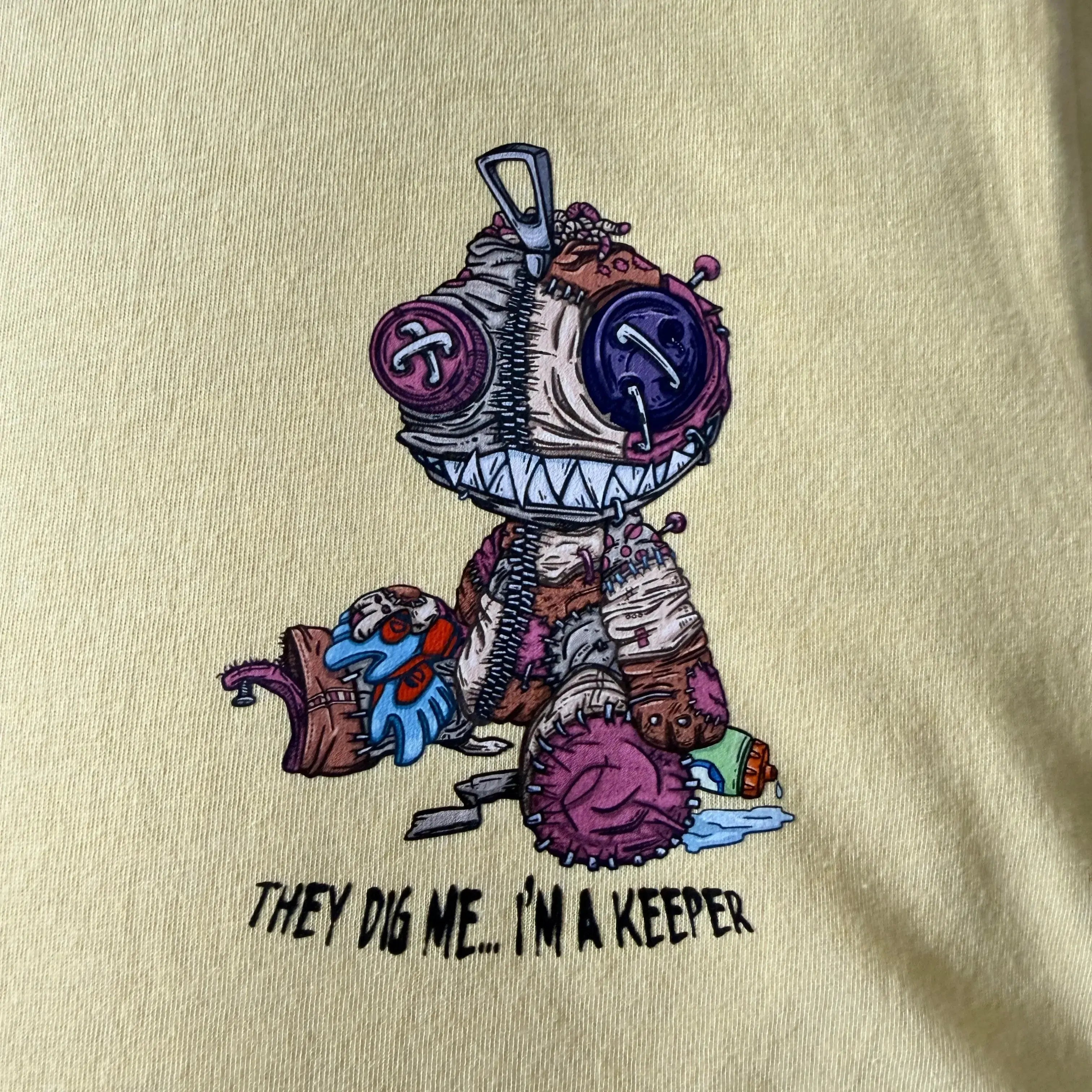 Beige t-shirt with a cartoon character and text on a beige background